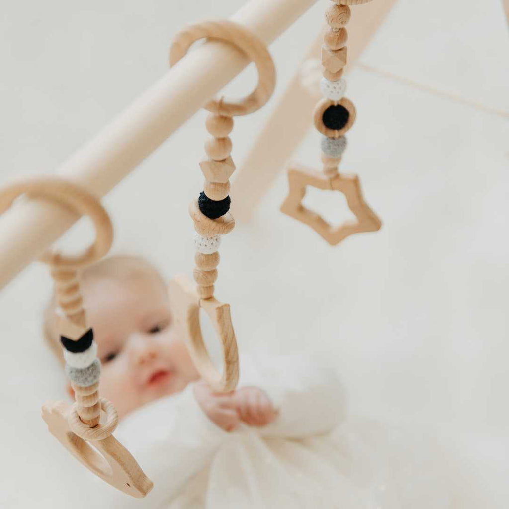 Holz-Babyspielbogen mit schwarz-weißem Spielzeug