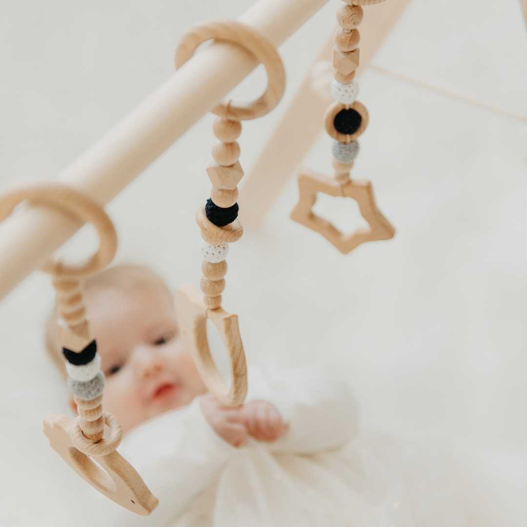Holz-Babyspielbogen mit schwarz-weißem Spielzeug